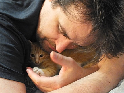 Man holding kitten's paw in his hand